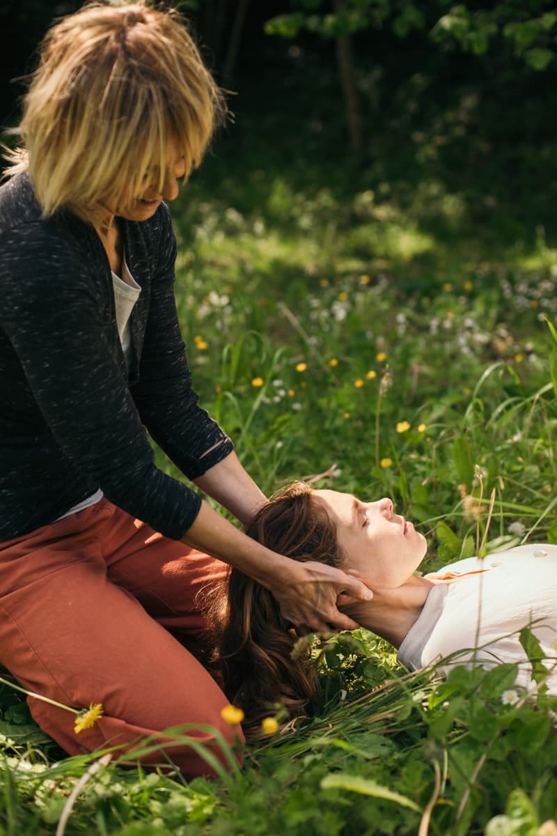 una profesora de yoga dándole un masaje en la cabeza a una alumna en medio de la naturaleza en bizkaia