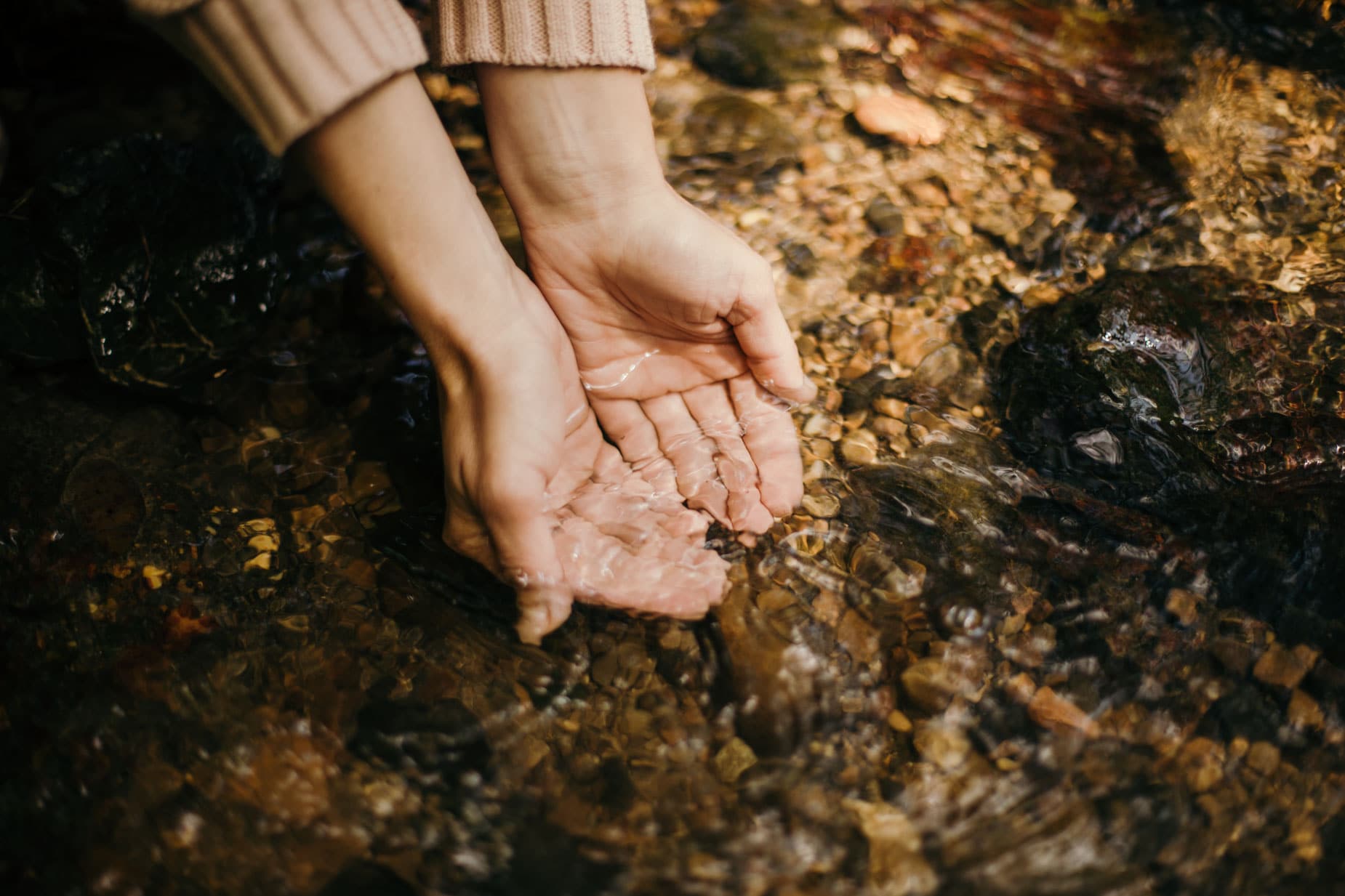 dos manos tomando agua de un rio