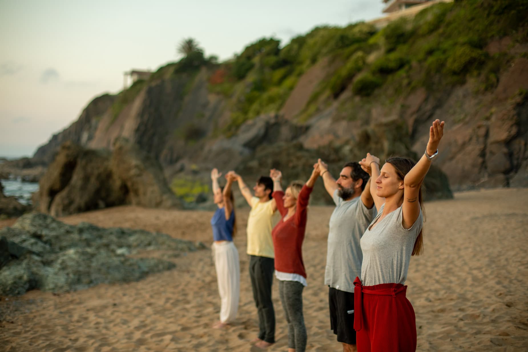 un grupo de practicantes de yoga con ana urrutia haciendo yoga en la playa